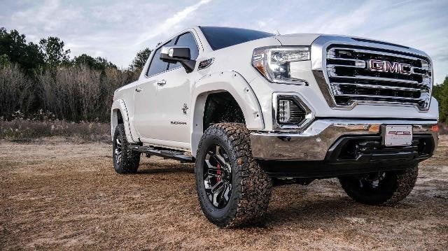 Muddy GMC truck parked outside near the forest