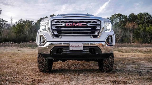 A white GMC truck covered in mud in the bottom half