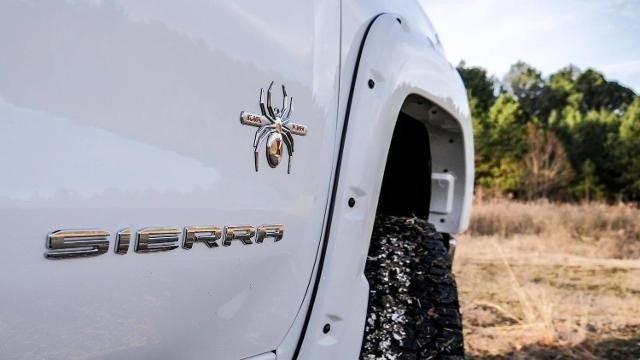 Close up view of a white GMC Sierra with a spider logo on it